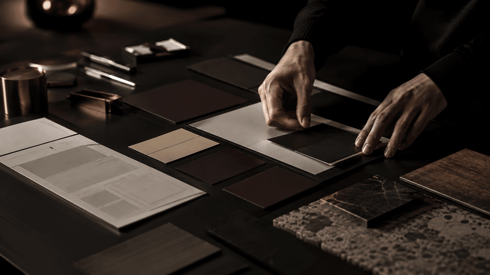 Hands arranging material and color samples on a dark table